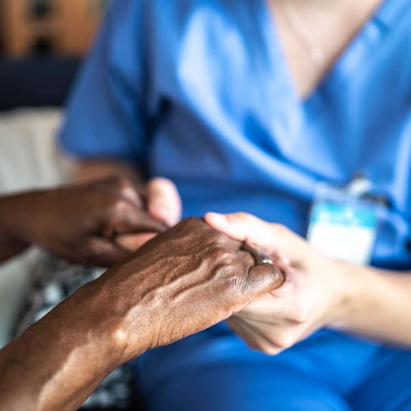 female caregiver holding female senior woman's hands