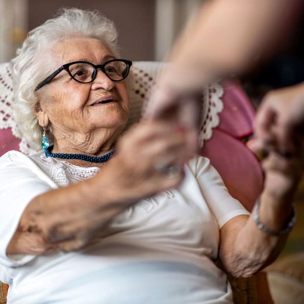 someone helping elderly lady up from a chair