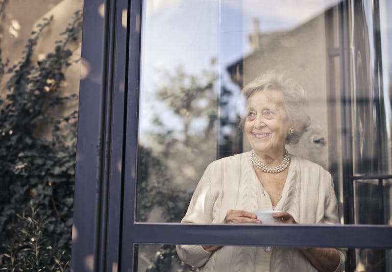 a woman holding a cup looking out a window